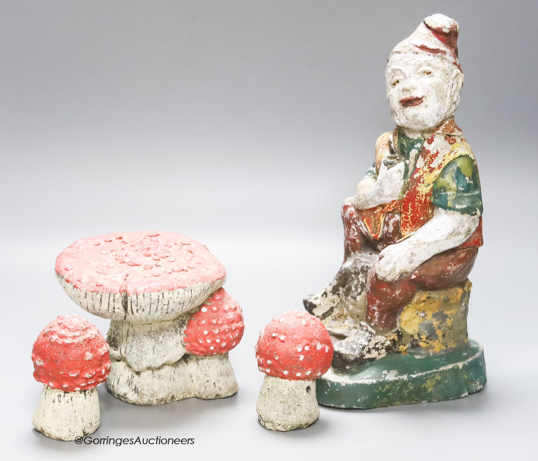 A composition seated garden gnome, height 29cm, and three toadstools (4)